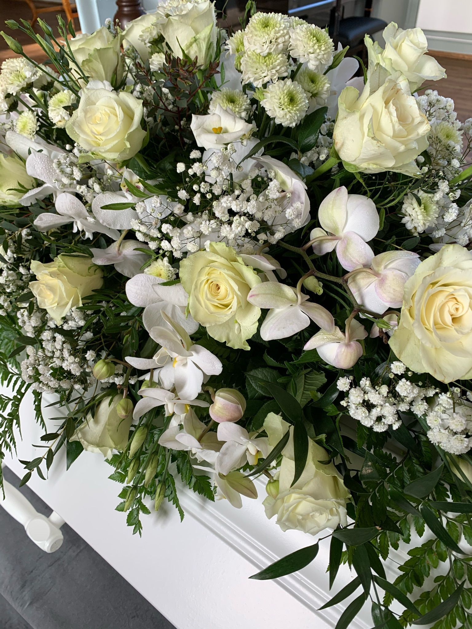 Hvit kistepynt med roser, orkidéer og brudeslør