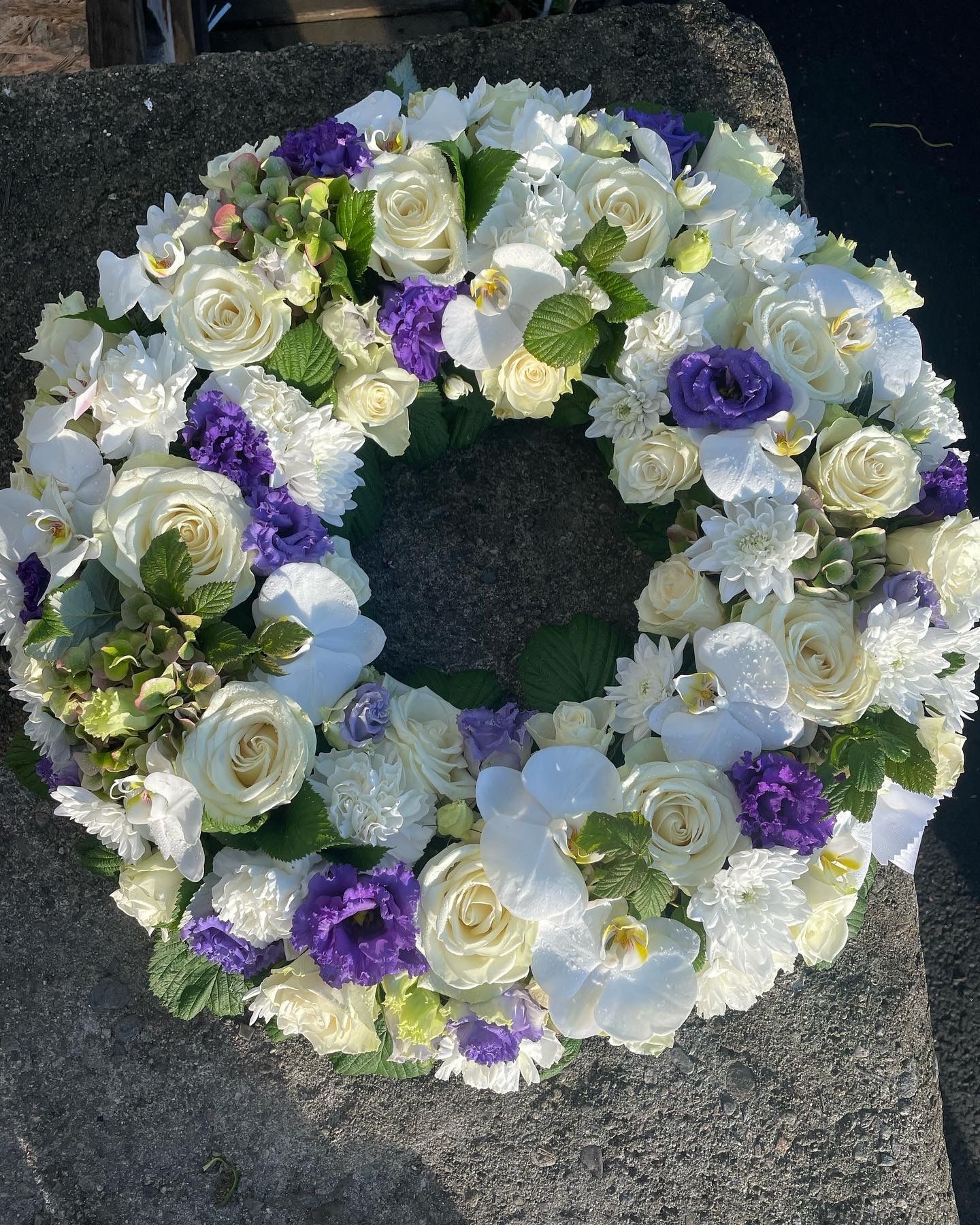 Krans i hvitt og lilla på naturstein