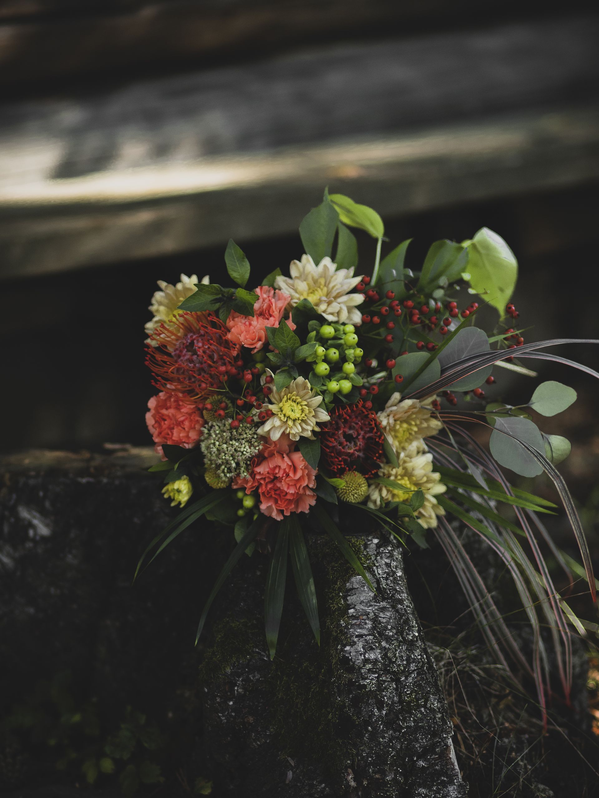 Liten bukett i fersken og rødt på trestubbe