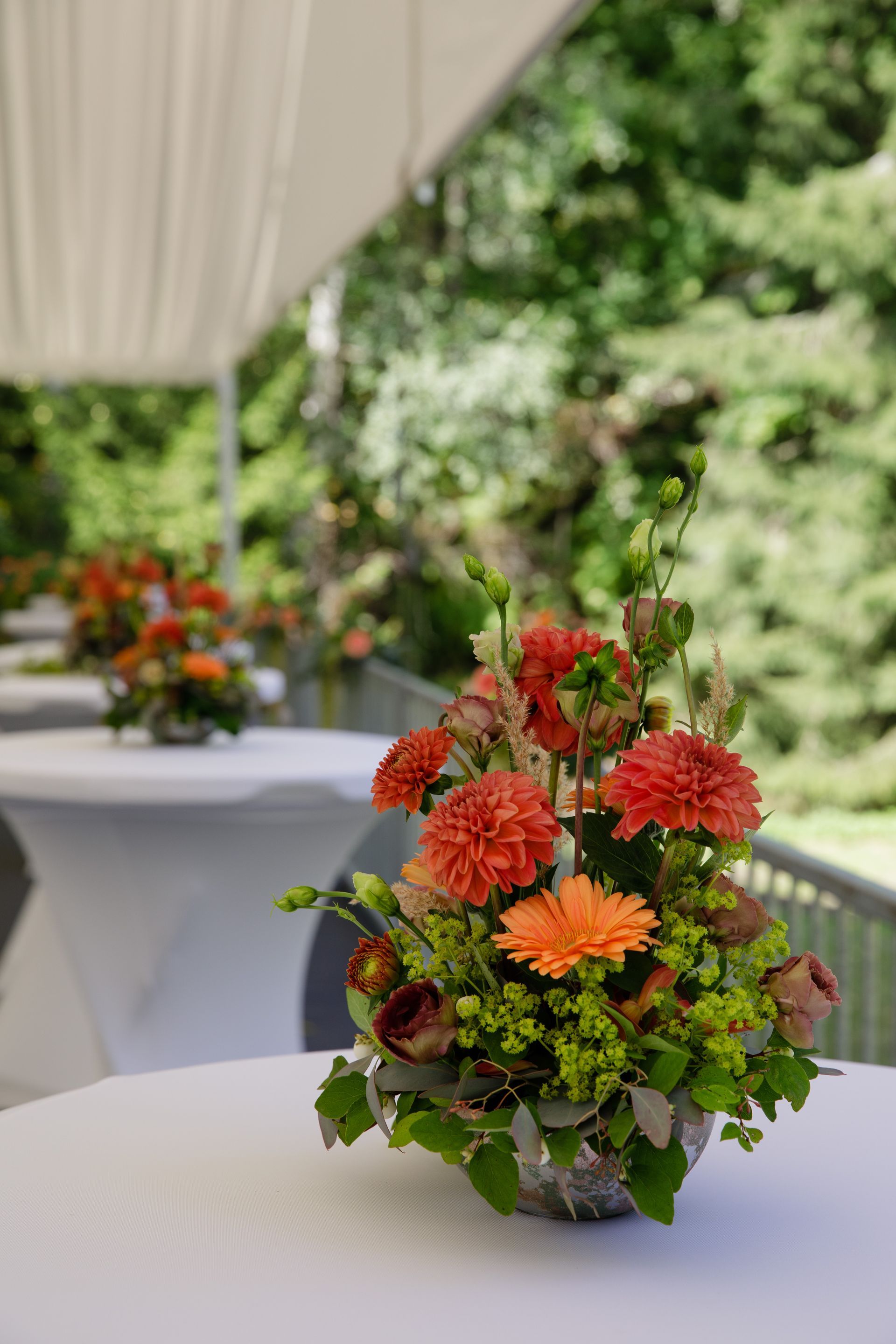 Borddekorasjon med oransje dahliaer og roser i selskapsteltet