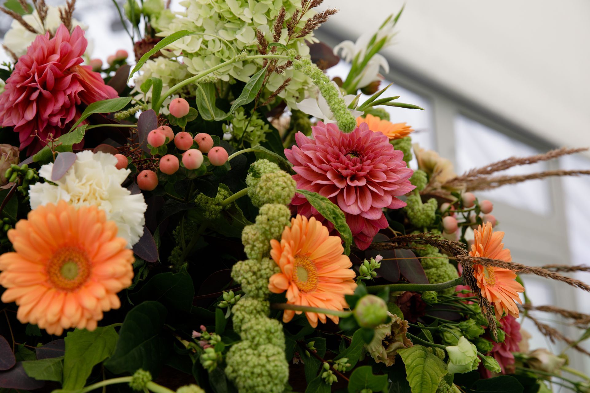 Nærbilde av borddekorasjon med dahliaer, gerbera og bær